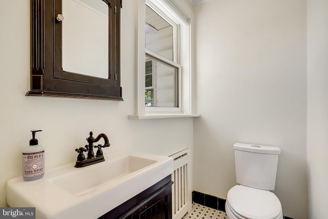 half bath featuring toilet, baseboards, and vanity