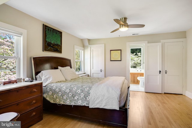bedroom with connected bathroom, visible vents, multiple windows, and light wood-style floors