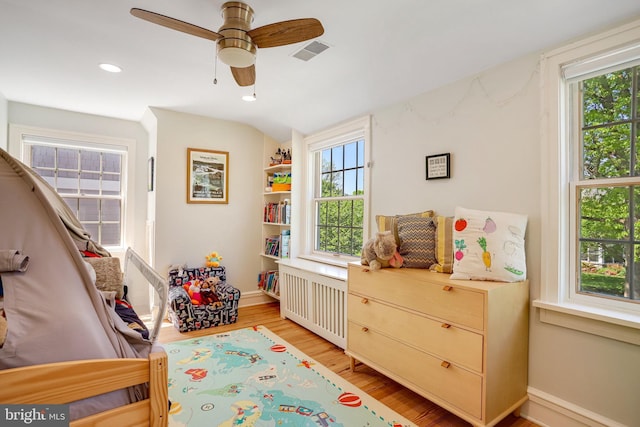 rec room featuring visible vents, plenty of natural light, radiator heating unit, and light wood finished floors