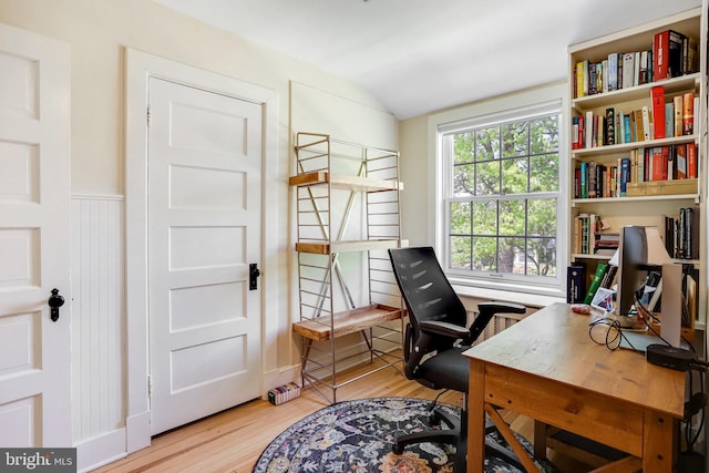 home office featuring wainscoting, light wood finished floors, and lofted ceiling