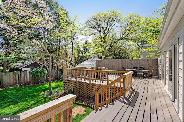wooden terrace featuring a yard, outdoor dining space, and a fenced backyard
