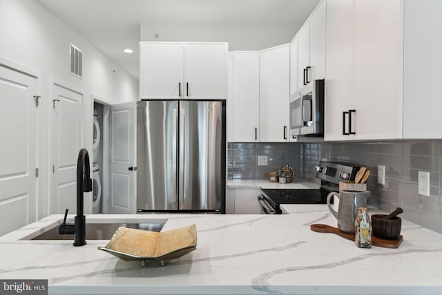 1810 Federal St Unit 1, Philadelphia, PA 19146 - kitchen featuring appliances with stainless steel finishes, stacked washer / dryer, light stone counters, decorative backsplash, and recessed lighting
