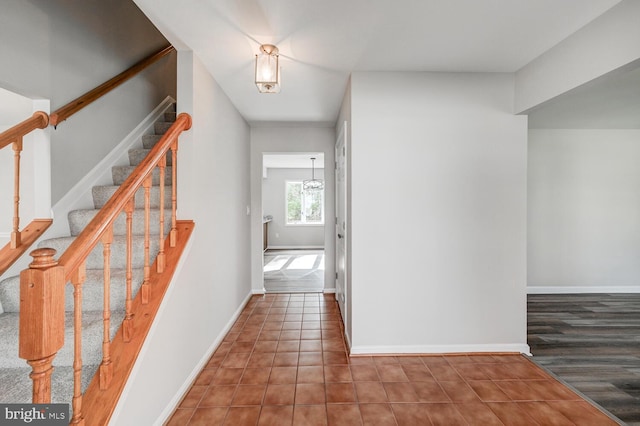 corridor featuring baseboards, tile patterned floors, and stairs