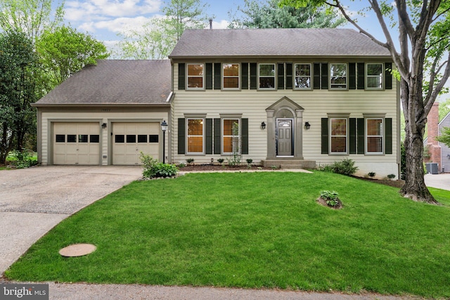 colonial home with an attached garage, a shingled roof, central AC unit, a front yard, and driveway