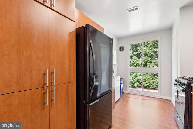 5608 Bismach Dr Unit 103, Alexandria, VA 22312 - kitchen featuring brown cabinetry, black appliances, light wood finished floors, baseboards, and visible vents