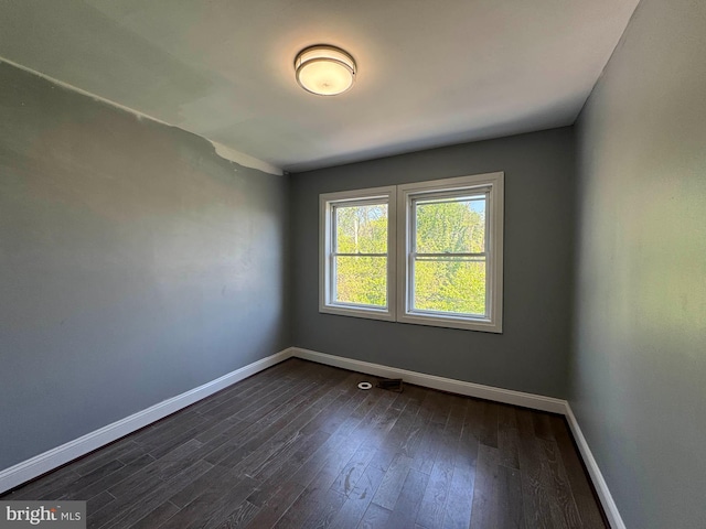 unfurnished room featuring baseboards and dark wood finished floors