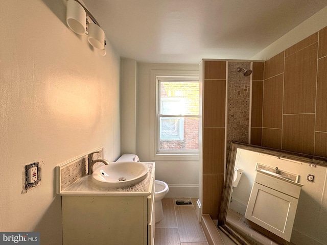full bath featuring toilet, visible vents, tiled shower, and vanity