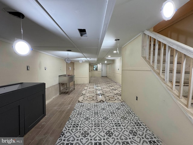 finished basement featuring stairway, crown molding, and wood finished floors