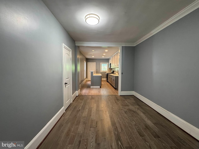 hall featuring baseboards, ornamental molding, and wood finished floors