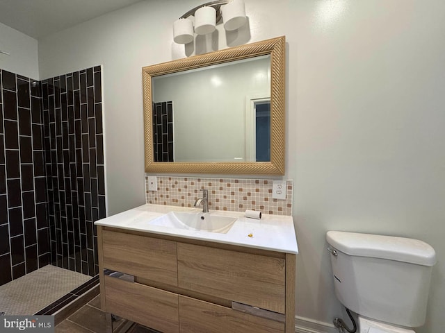 bathroom with vanity, decorative backsplash, a tile shower, and toilet