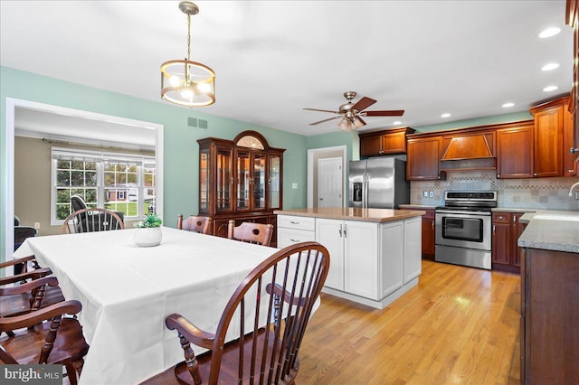 128 Pinion Pl, Bear, DE 19701 - kitchen with a center island, light wood-style flooring, tasteful backsplash, appliances with stainless steel finishes, and custom range hood