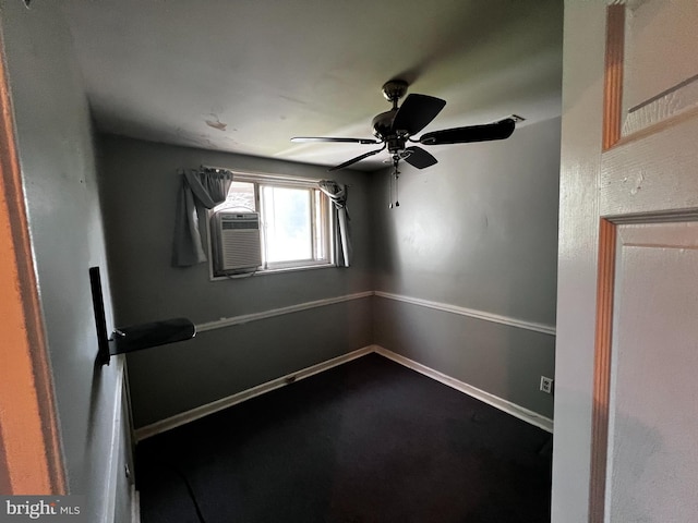 spare room featuring dark carpet, baseboards, ceiling fan, and cooling unit