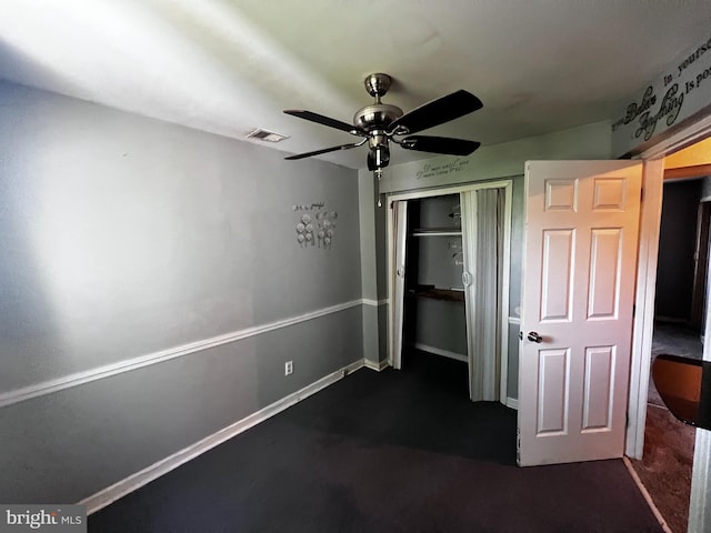 unfurnished bedroom with dark colored carpet, ceiling fan, visible vents, and a closet