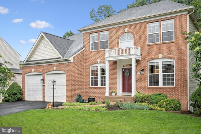 colonial inspired home with brick siding, a balcony, asphalt driveway, and a garage
