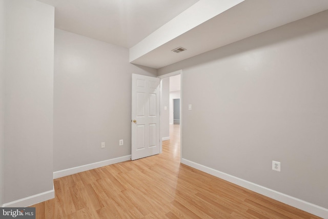 spare room featuring baseboards and light wood finished floors