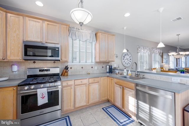kitchen with a sink, light brown cabinetry, a peninsula, appliances with stainless steel finishes, and visible vents