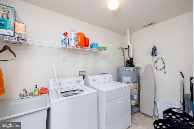 clothes washing area with washer and clothes dryer, a sink, water heater, laundry area, and visible vents