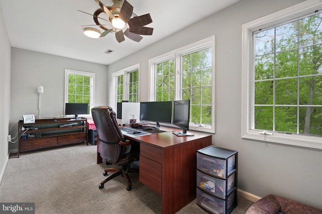 carpeted home office featuring baseboards, visible vents, a ceiling fan, and a healthy amount of sunlight