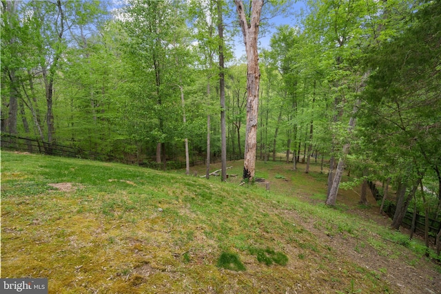 view of yard with a wooded view and fence