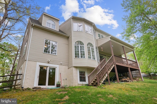 back of house featuring a deck, stairway, brick siding, fence, and a lawn