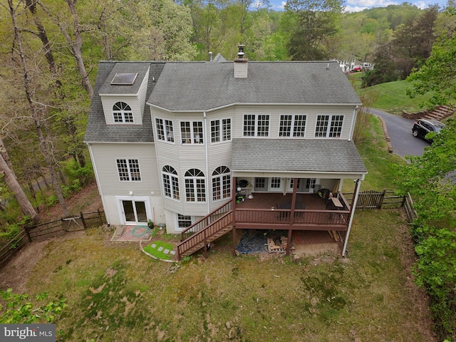back of property with a deck, a chimney, a shingled roof, a lawn, and a fenced backyard