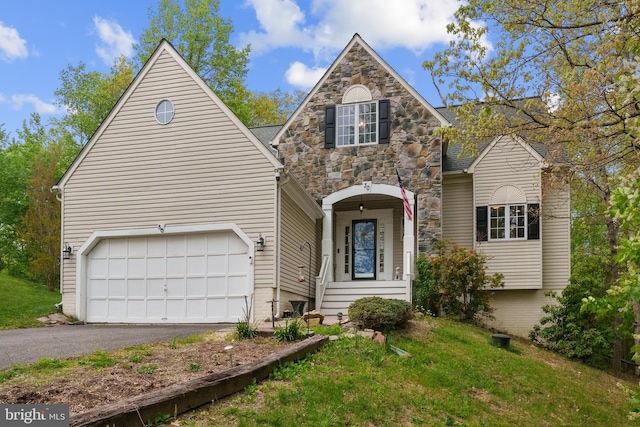 traditional-style house with stone siding, aphalt driveway, and a garage