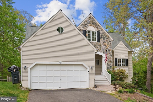 traditional-style house featuring roof with shingles, an attached garage, and aphalt driveway