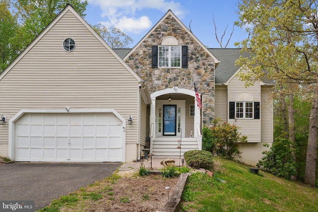 traditional-style home featuring aphalt driveway, a shingled roof, and stone siding