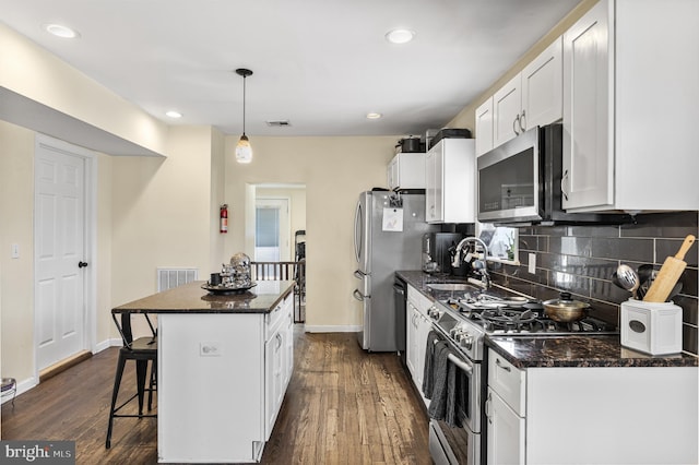 kitchen with a kitchen island, a breakfast bar area, white cabinetry, a sink, and stainless steel appliances