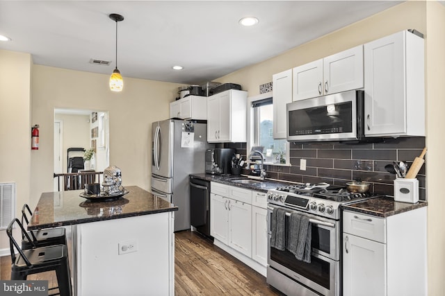 kitchen with a kitchen island, a sink, white cabinets, a breakfast bar, and stainless steel appliances