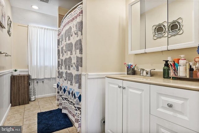 bathroom featuring vanity, tile patterned floors, visible vents, and a wainscoted wall