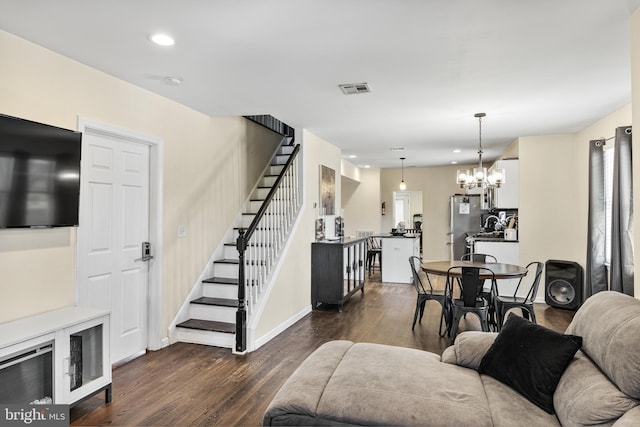 living room featuring an inviting chandelier, visible vents, stairs, recessed lighting, and dark wood-type flooring