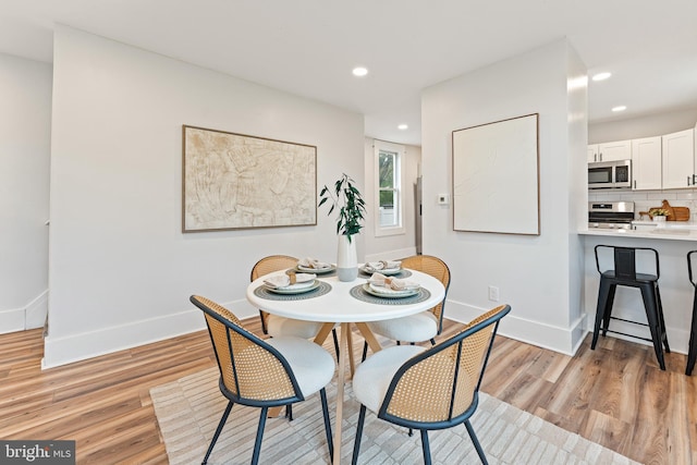 dining room with light wood-style floors, baseboards, and recessed lighting