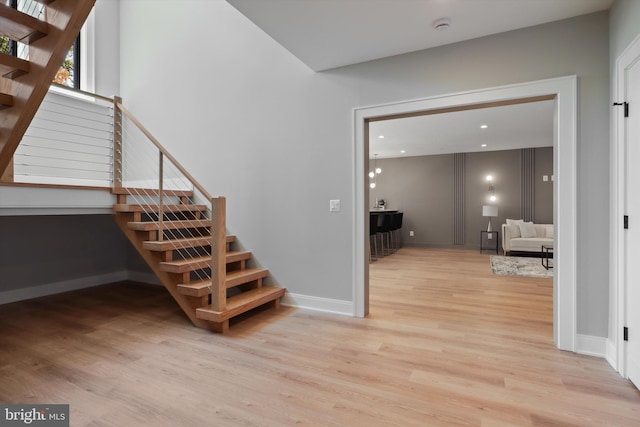 stairway with baseboards, wood finished floors, and recessed lighting
