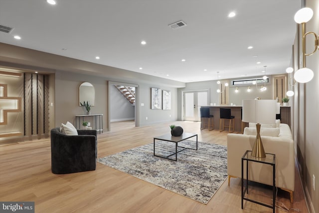 living area featuring light wood-style flooring, visible vents, recessed lighting, bar, and stairs