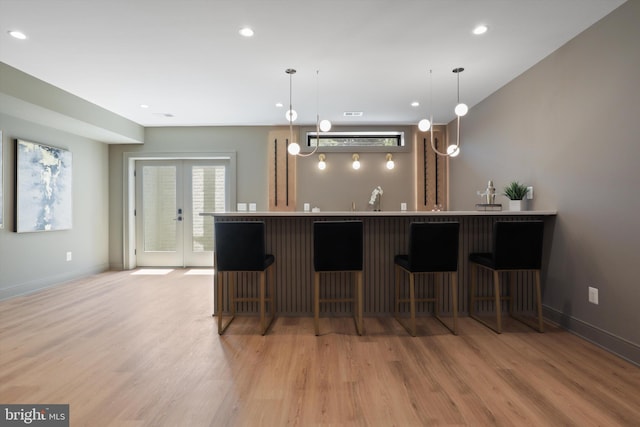 kitchen featuring a breakfast bar, light wood-style flooring, baseboards, and a sink