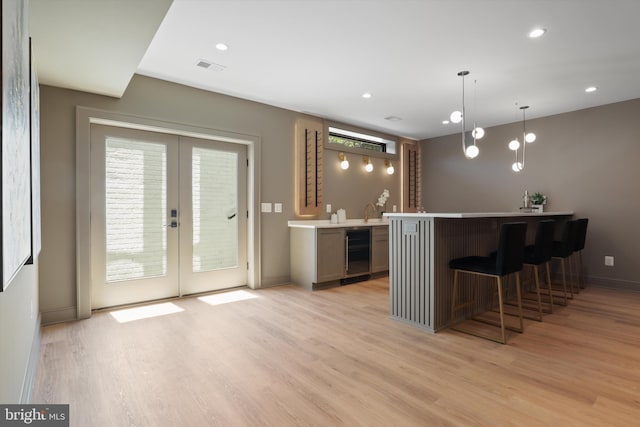 bar with light wood-type flooring, wine cooler, visible vents, and wet bar