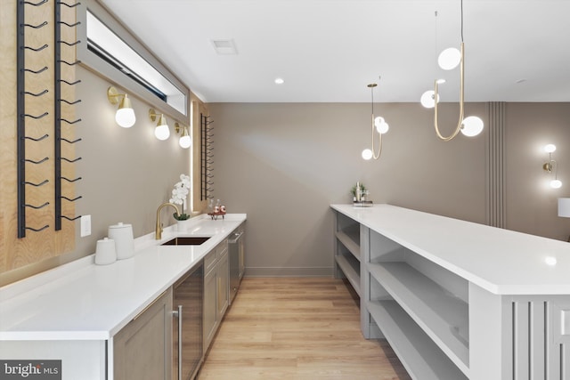 bar featuring light wood finished floors, a sink, baseboards, pendant lighting, and beverage cooler