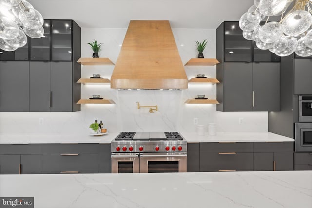 kitchen with open shelves, gray cabinetry, stainless steel appliances, and custom range hood