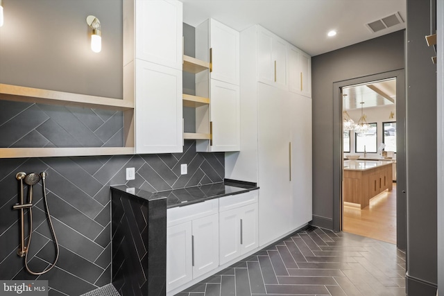 kitchen with white cabinets, decorative backsplash, open shelves, and visible vents
