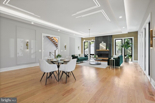 dining area featuring light wood finished floors, visible vents, recessed lighting, stairs, and a raised ceiling