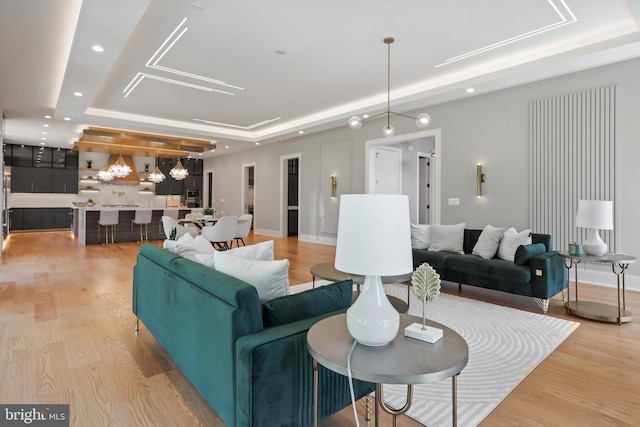 living area featuring recessed lighting, a tray ceiling, and light wood-style flooring