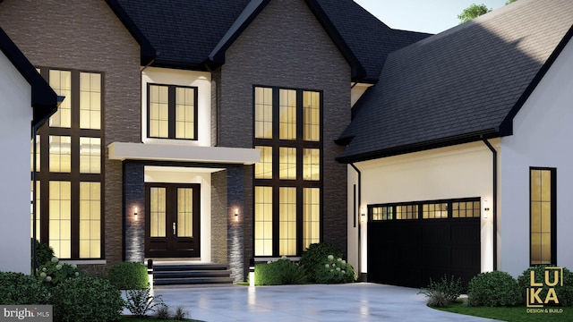 view of front of home with a garage, concrete driveway, french doors, and stucco siding