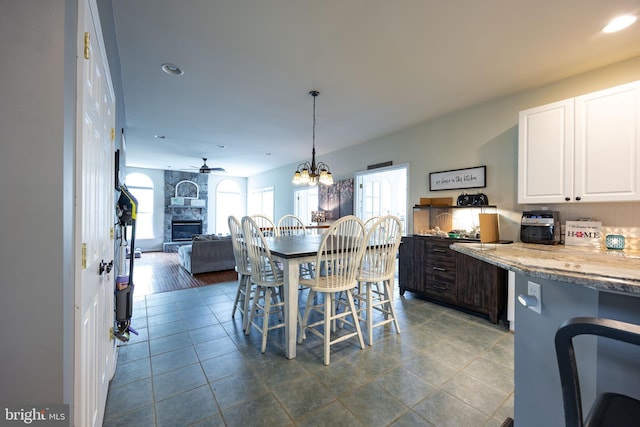350 Rotterham Dr, Hedgesville, WV 25427 - dining space featuring recessed lighting, ceiling fan with notable chandelier, a stone fireplace, and dark tile patterned flooring