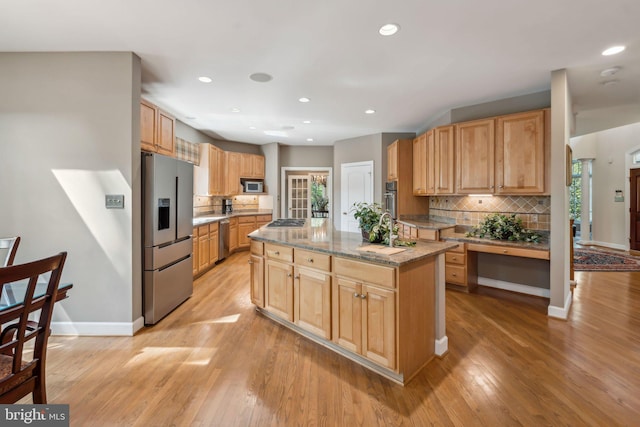 kitchen featuring stainless steel appliances, decorative backsplash, light wood-style flooring, and a sink