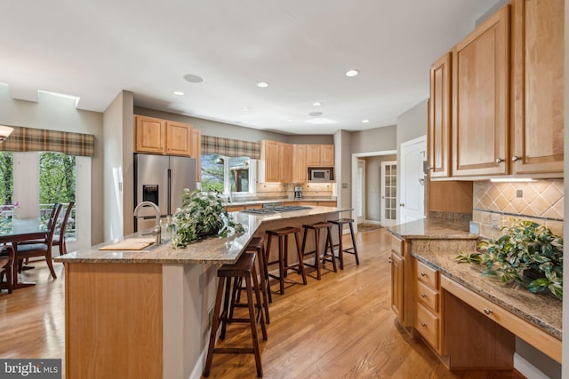 kitchen with decorative backsplash, a sink, appliances with stainless steel finishes, a breakfast bar, and a center island