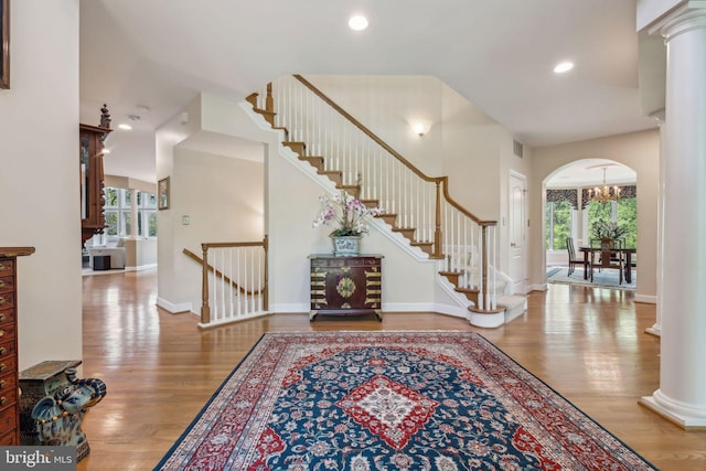 foyer entrance featuring arched walkways, wood finished floors, and ornate columns