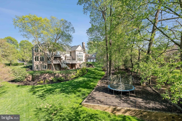 view of yard featuring a wooden deck, a trampoline, and stairway