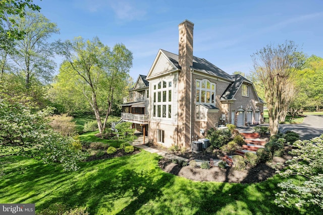 view of side of property with central AC, a chimney, a wooden deck, and a yard