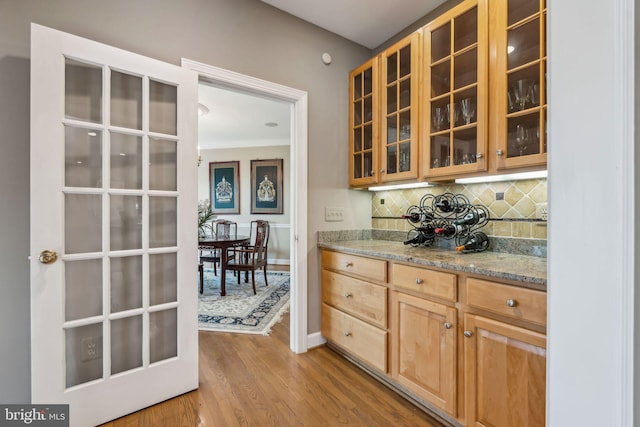 bar featuring wood finished floors, baseboards, and backsplash